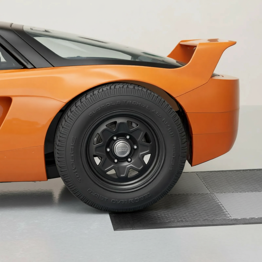 Orange sports car parked on dark grey interlocking garage floor tiles with edge transition strip visible